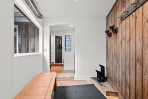 A hallway with a wooden table, a black fireplace, and a wooden wall with hooks. - Scenic Rt 4: Hot tub, minutes to everything! (Bridgewater)
