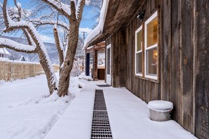 A wooden building with a snow-covered exterior, a metal grate, and a wooden fence. - Scenic Rt 4: Hot tub, minutes to everything! (Bridgewater)