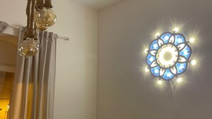 Una habitación con lámpara colgante, luz decorativa en la pared y una cortina.