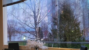 A modern interior with a large window, a table with chairs, and string lights. - Lakeside Serenity in Lutakko | sauna, parking, A/C (Jyväskylä)
