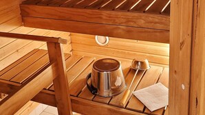 A wooden sauna with a bench, a small table, and a metal container. - Lakeside Serenity in Lutakko | sauna, parking, A/C (Jyväskylä)