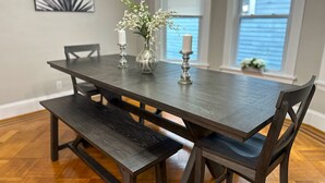 Een eettafel met banken, kaarsen en een vaas met bloemen.