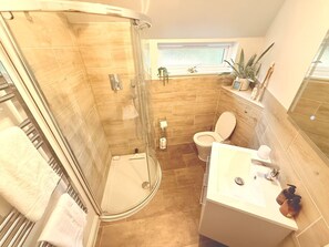 A bathroom with a glass-enclosed shower, a toilet, and a sink with a mirror.