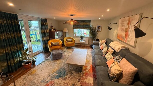 Un salon moderne avec un canapé, des fauteuils, une table basse et une grande fenêtre.