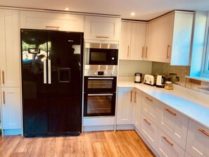A modern kitchen with white cabinetry, a black refrigerator, a built-in oven, and a countertop with a toaster and other appliances.