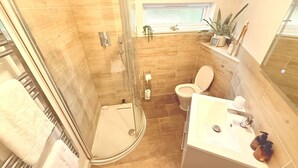 Une salle de bain avec une douche à parois de verre, des toilettes et un lavabo avec un miroir.