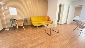 En moderne stue med en gul sofa, et lille bord og en fletstol.