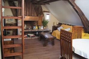 A cozy loft-style room with a brick fireplace, wooden furniture, and a yellow sofa. - Le perchoir de St-Antoine - view of Honfleur harbour, Netflix, games, vinyls (Honfleur)