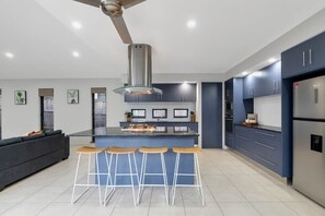 Eine moderne Küche mit einer zentralen Kochinsel, Barhocker und Deckenventilator.