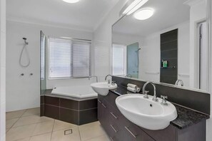 Un bagno moderno con una vasca, due lavabi, un grande specchio e una doccia.