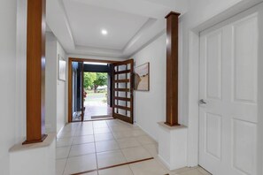 A hallway with a wooden door, white walls, and a tiled floor.
