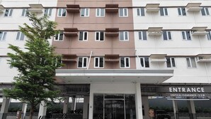 Un immeuble à plusieurs étages, dont l’entrée est signalée par l’inscription « ENTRÉE », et dont la hauteur maximale autorisée pour le passage des véhicules est de 2,2 mètres.