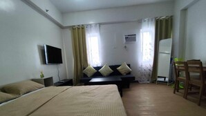 Une chambre d’hôtel avec deux lits, un téléviseur à écran plat, un canapé avec des coussins, un bureau et une chaise.