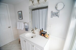 A bathroom with a white sink, a mirror, a shower curtain, and a towel rack.