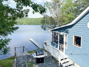 Un chalet au bord du lac, avec un quai, un barbecue et une vue sur le lac.
