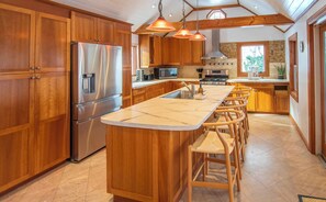 A kitchen with wooden cabinets, stainless steel appliances, a marble countertop, and pendant lighting. - Charming Lakefront Cottage on Lake Mascoma (Enfield)