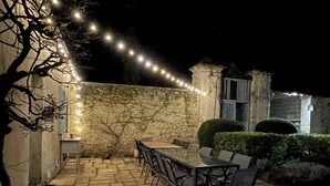 Eine Terrasse im Freien mit Steinboden, einem Tisch und Stühlen.