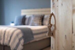A bed with a striped blanket and a rope tied to a wooden headboard. - Blue Horizon - Spectacular Coastal Views (Penally)