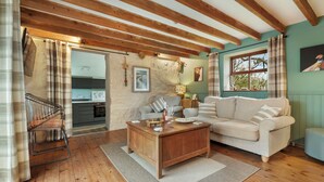 A cozy living room with a wooden coffee table, a beige sofa, and a kitchen in the background.