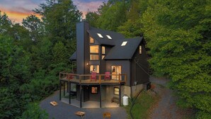 Een meerlaags huis met een balkon, omgeven door bomen.