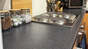 Una cocina con armarios de madera, microondas, cocina a gas y frascos de especias.