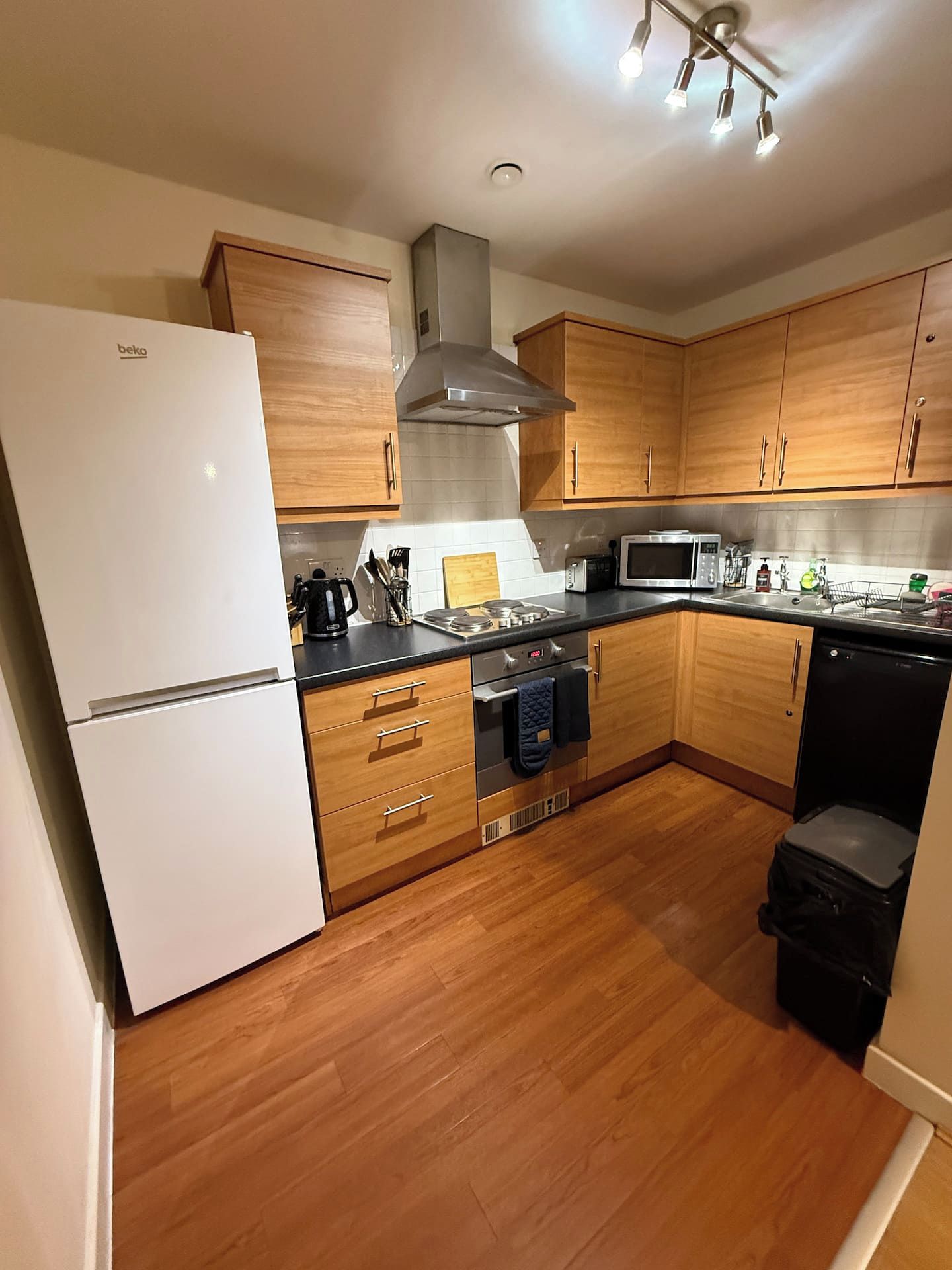 A modern kitchen with wooden cabinets, a white refrigerator, a microwave, and a dishwasher.