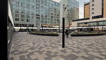 A plaza with a checkered floor pattern, modern buildings, and a clear sky.