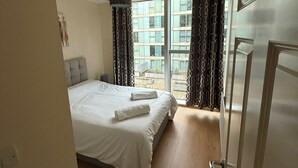 Un dormitorio con una cama grande, una lámpara colgante y vistas a un balcón con cortinas estampadas.
