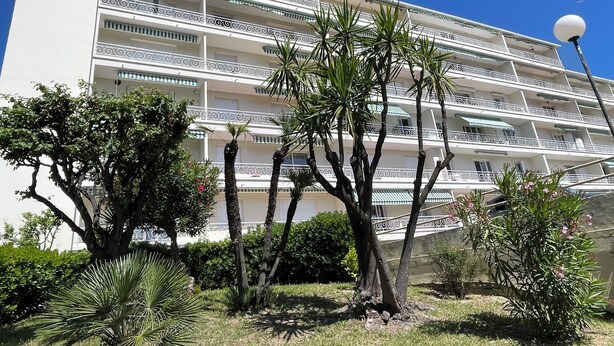 A multi-story hotel with balconies, surrounded by tropical plants and a clear blue sky. - CANNES-Vue mer -Superb T2-3 stars -Heating/air-conditioning-Parking (Cannes)