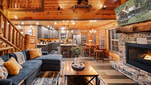 A log cabin interior with a living room, dining area, kitchen, and a fireplace. - Indoor Pool Cabin, Hot Tub & Theater Room, Near Dollywood, Game Room, Sleeps 14 (Pigeon Forge)