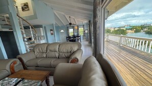 Un área de estar acogedora con un sofá, sillones, una mesa de comedor y vista al agua.