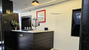 A reception desk with a dark wood finish, a potted plant, and a framed artwork on the wall. - Hotel Golden Tulip'z (Gorakhpur)