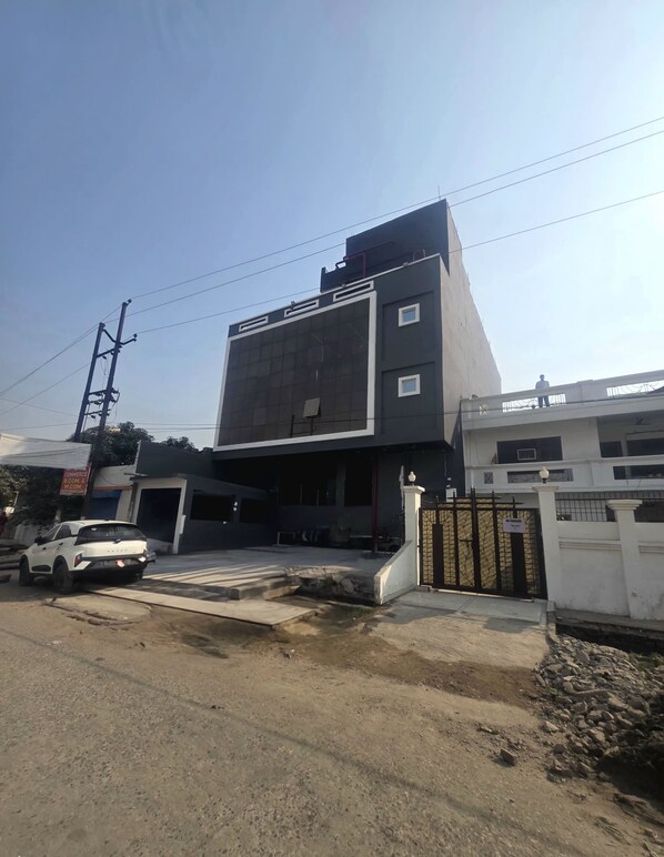 Un edificio moderno con un gran muro de vidrio, una entrada porticada y un coche blanco estacionado al frente.