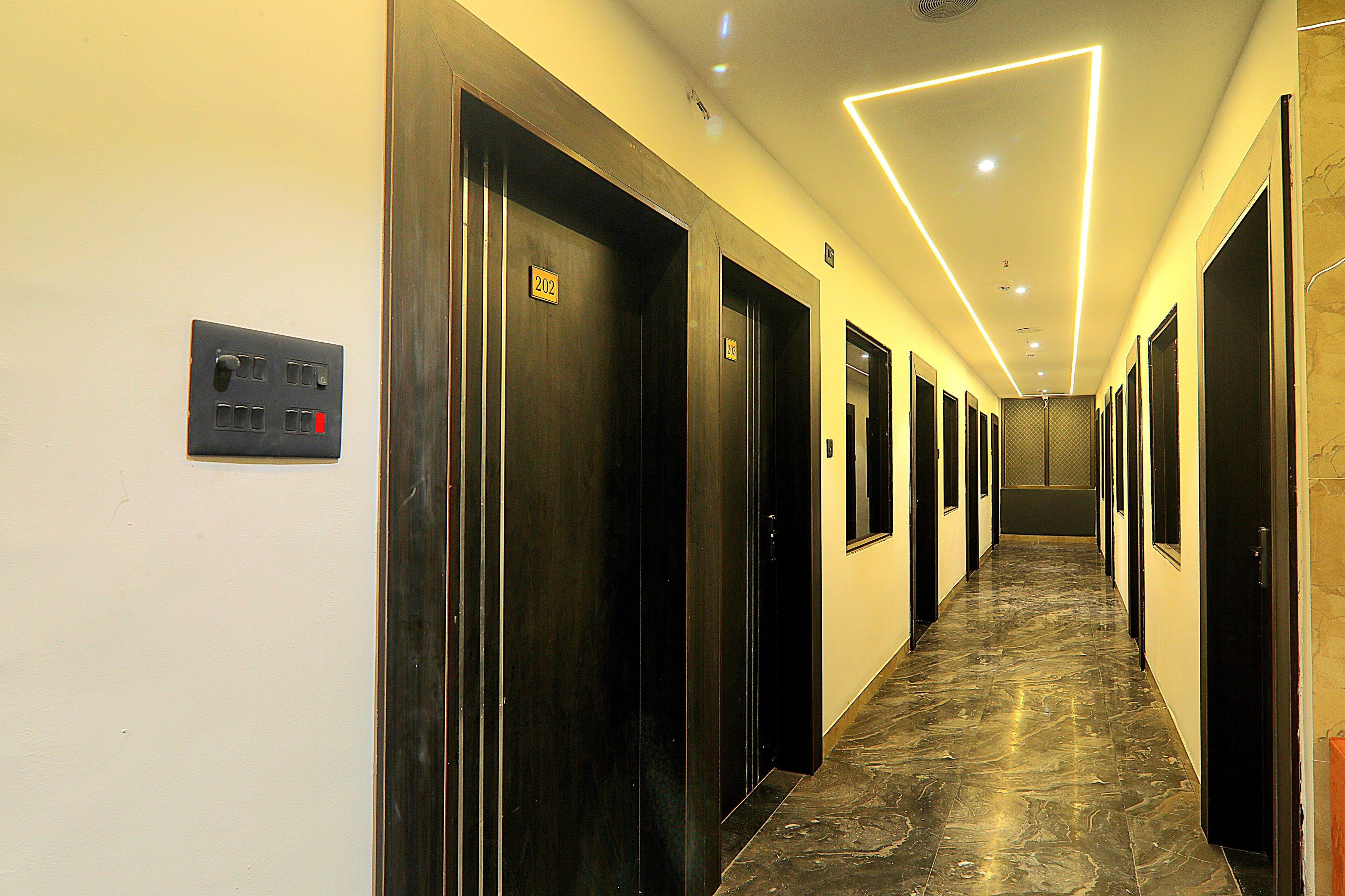 A hotel hallway with doors numbered 202 and 203, a control panel, and a marble floor.