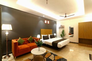 Une chambre d’hôtel moderne équipée d’un lit, d’un canapé, d’une petite table et d’un ventilateur de plafond.