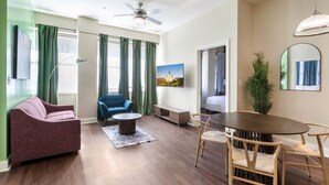 Una sala de estar moderna con un sofá, un sillón azul, una mesa de centro y una mesa de comedor con sillas.