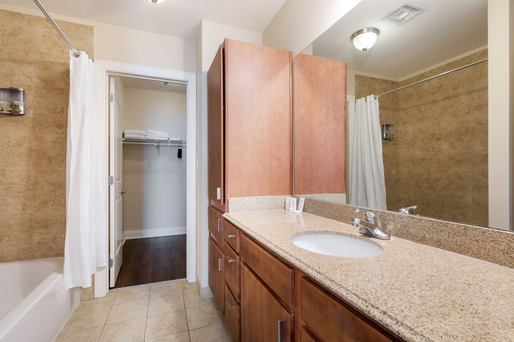 A bathroom with a sink, mirror, and wooden cabinets.