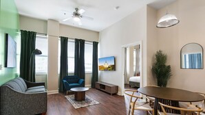 Una sala moderna con un sofá, un sillón azul, una mesa de centro y un comedor con una mesa y sillas.