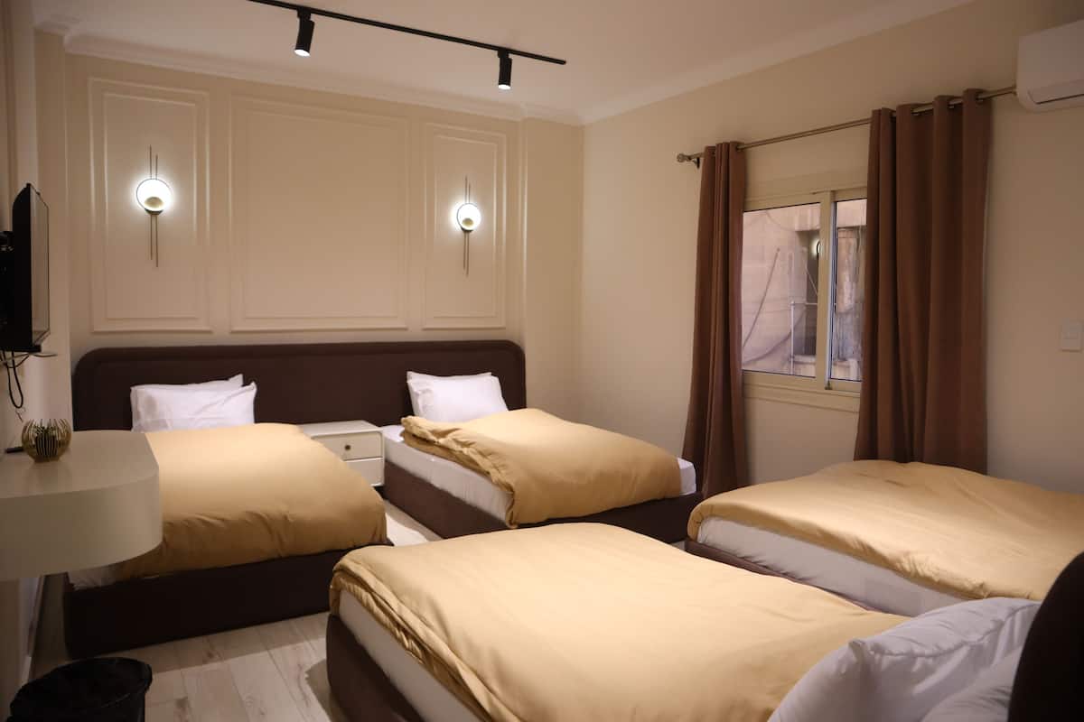 A hotel room with two beds, a desk, and a window with curtains.
