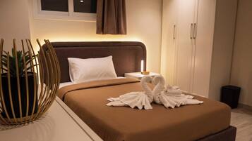 A hotel room with a bed, a bedside table with a lamp, a potted plant, and a wardrobe.
