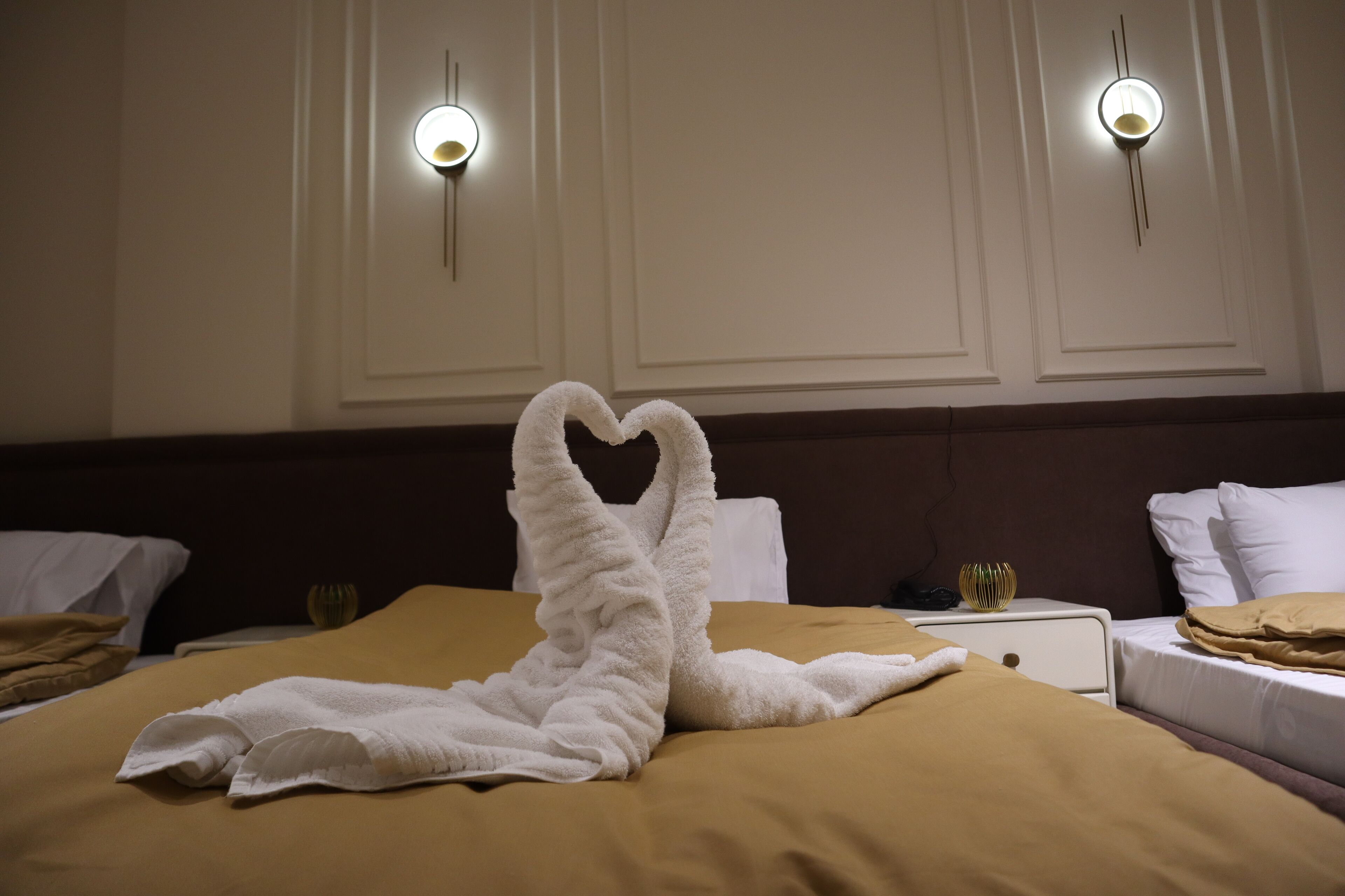 A hotel room with a bed, two wall sconces, a nightstand, and a decorative vase.