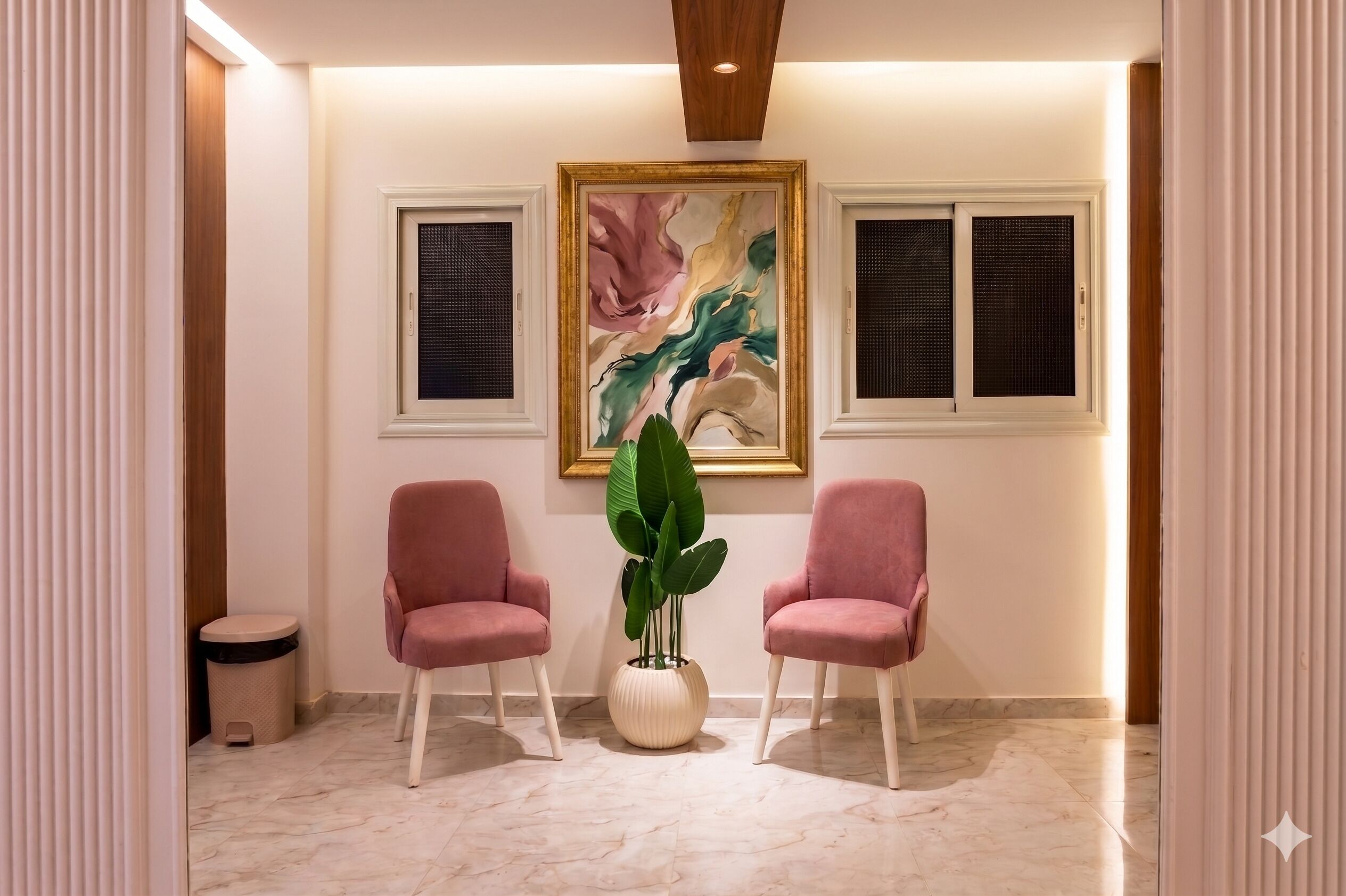 Un couloir avec deux chaises roses, une grande peinture abstraite et une plante en pot.