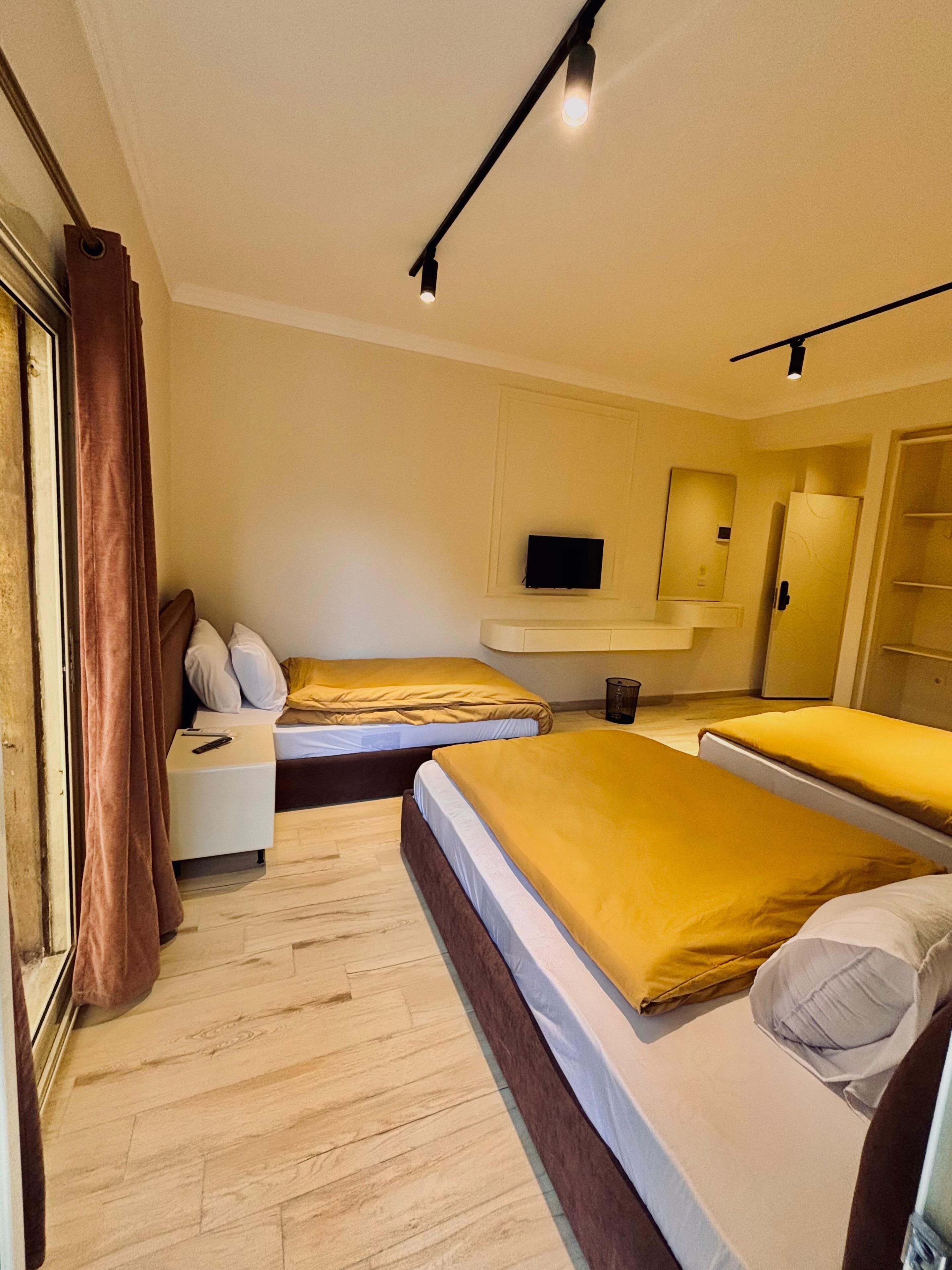 A hotel room with two beds, a TV, a mirror, and a wardrobe.