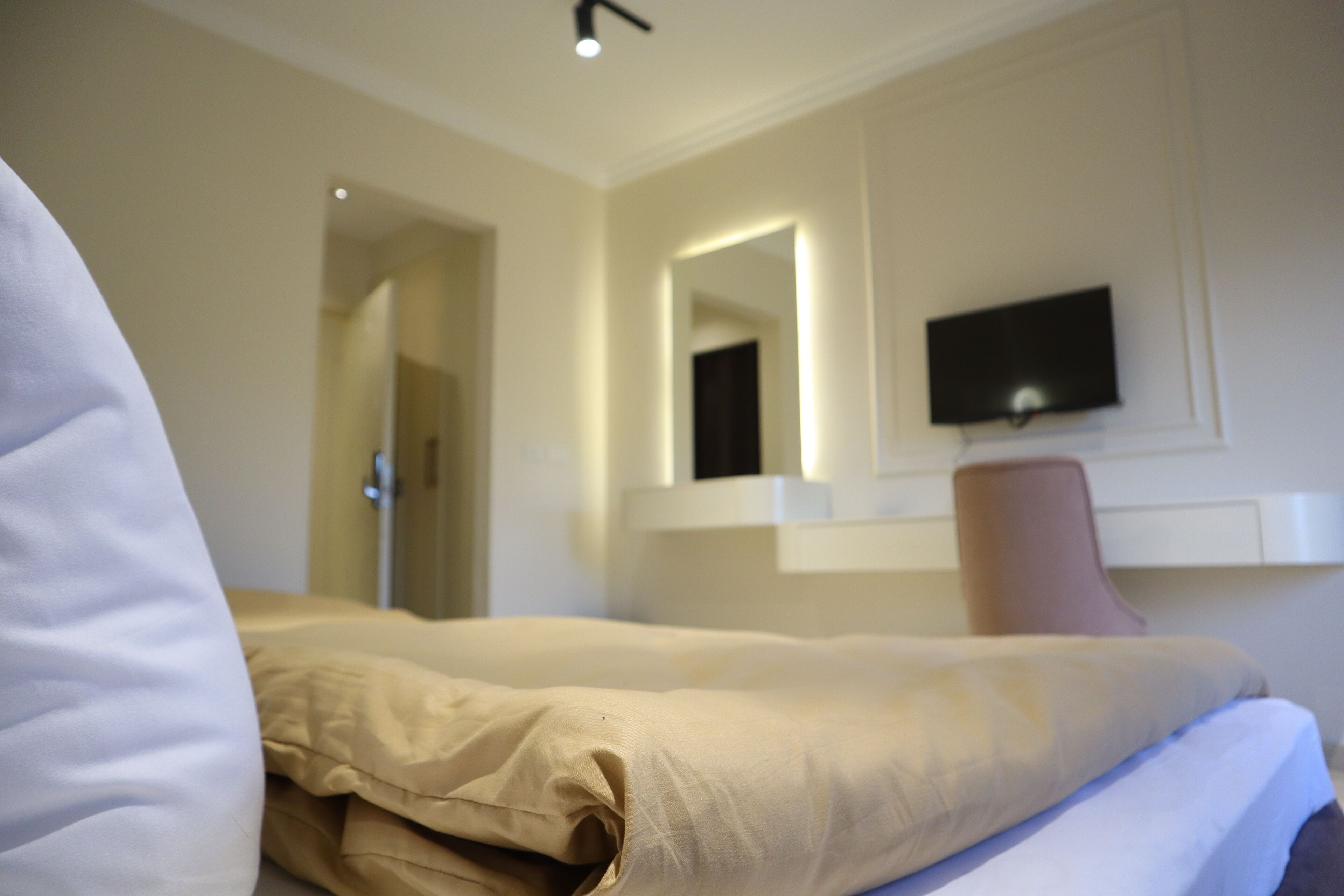 Une chambre d’hôtel avec un lit, un téléviseur fixé au mur et une porte donnant sur une autre pièce.