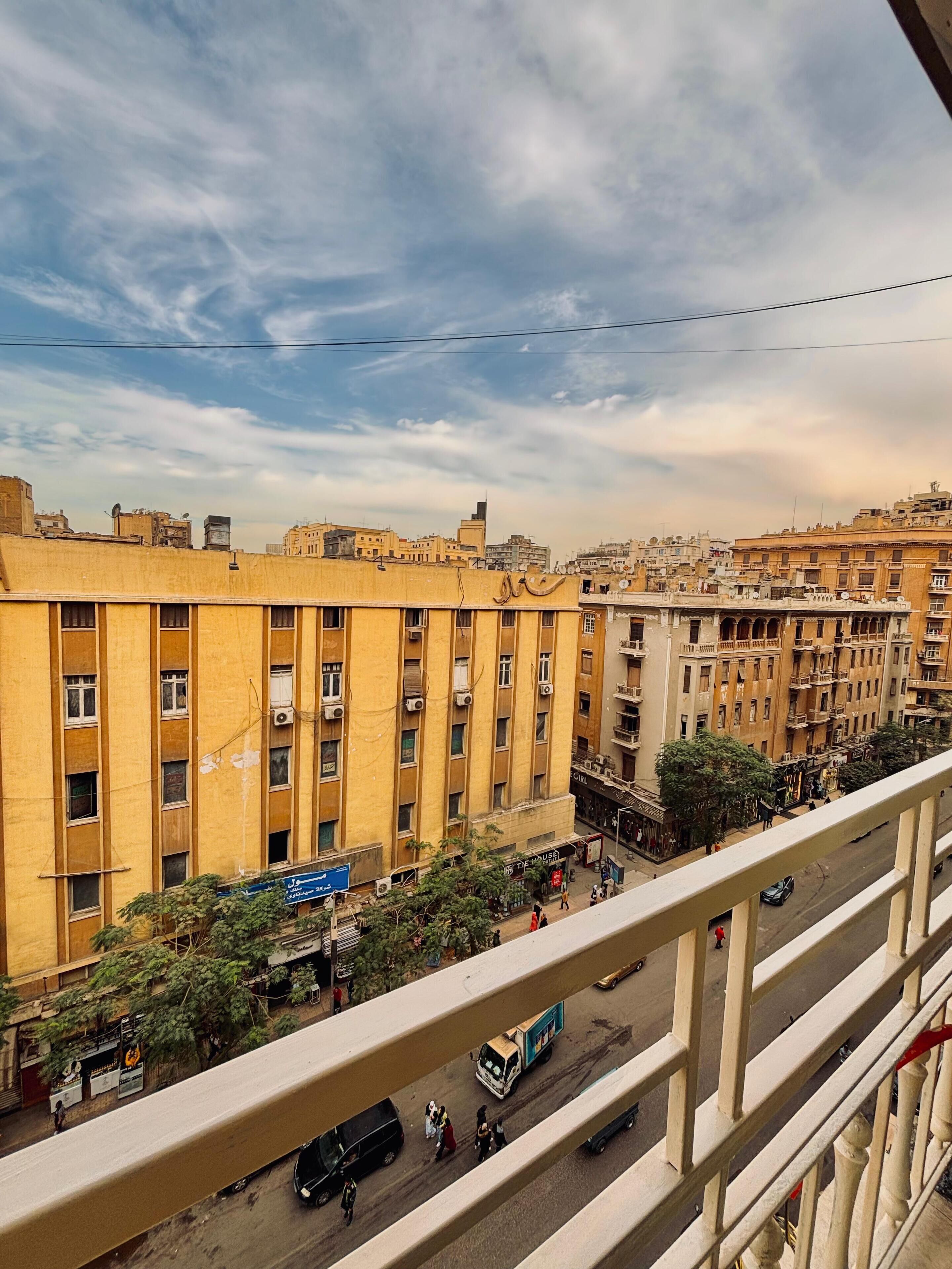 A high-rise building with multiple floors, balconies, and a busy street below.