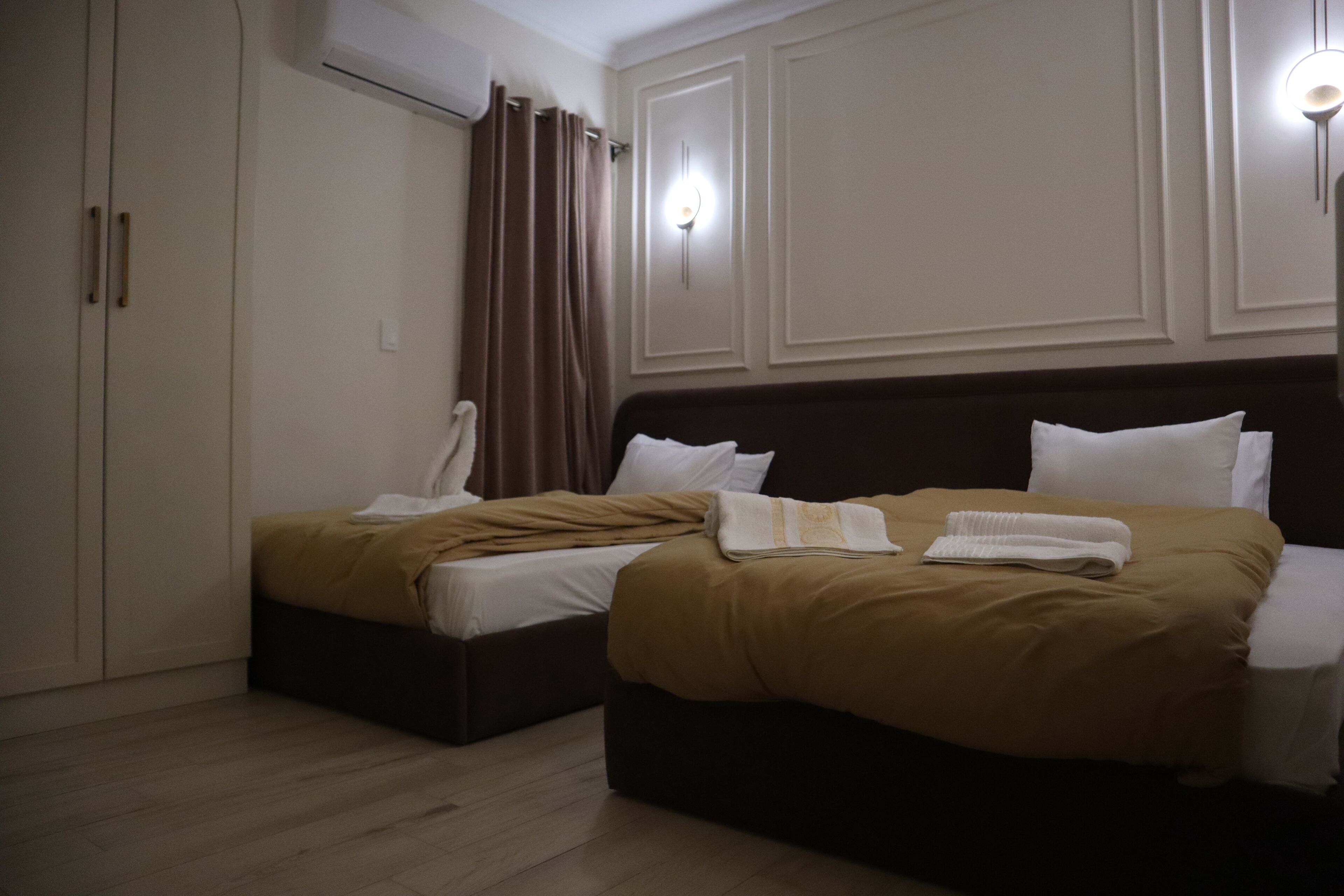 A hotel room with two beds, a wardrobe, and a shower.