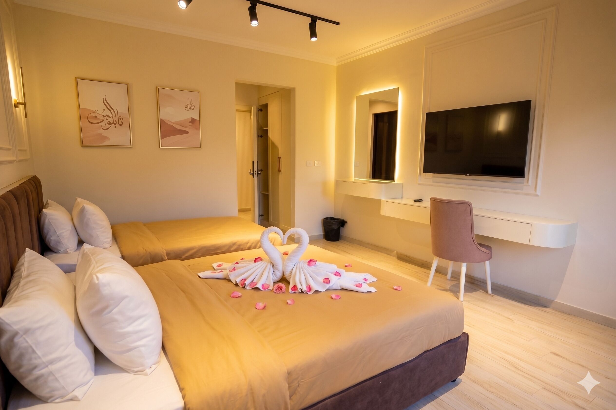 A hotel room with two beds, a TV, a desk, and artwork on the wall.