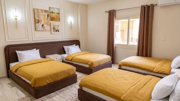 A hotel room with two beds, a large window with curtains, and wall-mounted artwork.