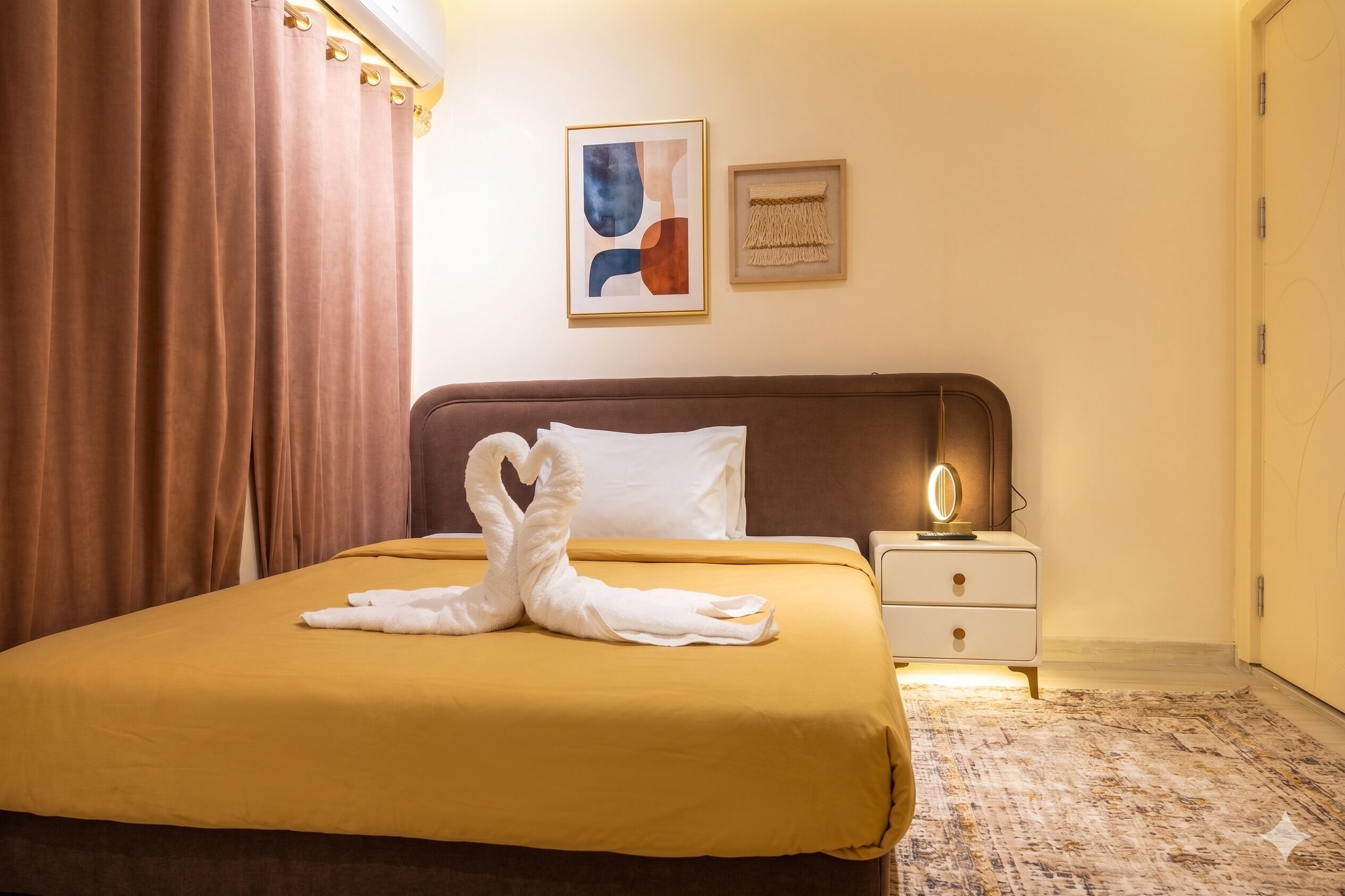 A hotel room with a bed, a nightstand, a mirror, and artwork on the wall.