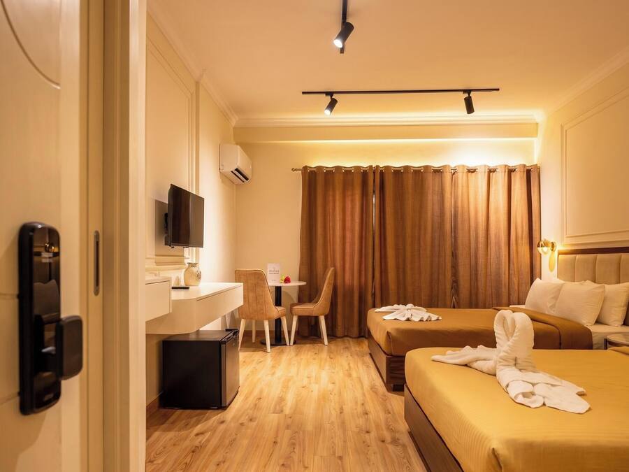 A hotel room with a desk, two beds, a television, and a bathroom door.